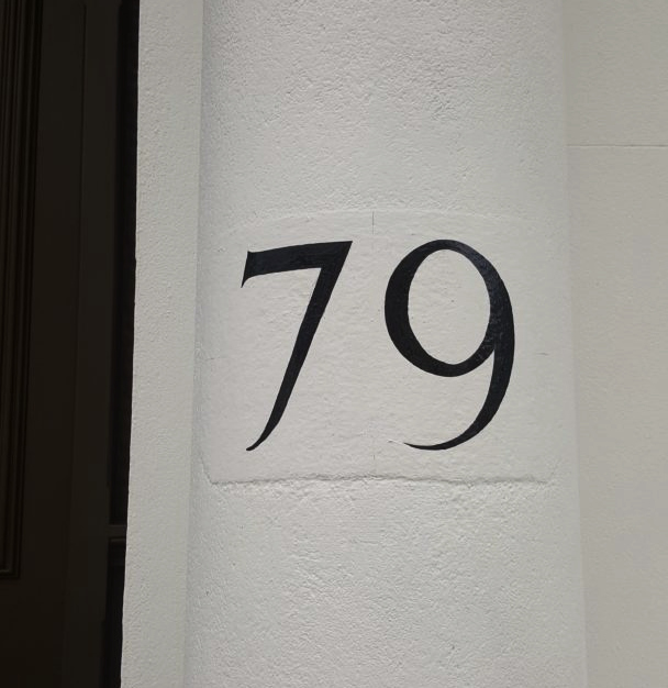 Roman serif house numbers on rendered entrance pillar