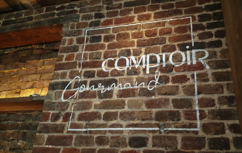 White business signwriting painted onto exposed Victorian brickwork in a Soho commercial interior.