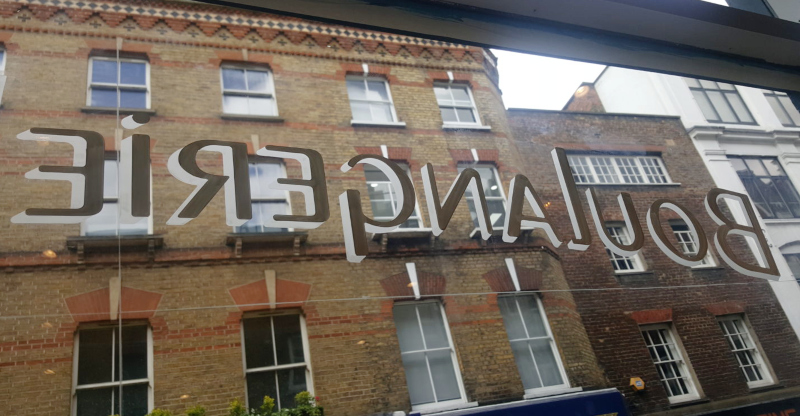 Completed white glass lettering with gilding size applied ready for 23ct gold leaf at Comptoir Gourmand in Soho, London.