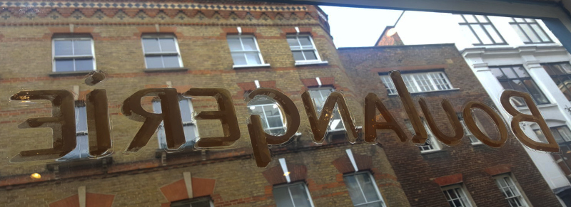 Protective varnish being applied over reverse-painted and gilded glass lettering in Soho, London.