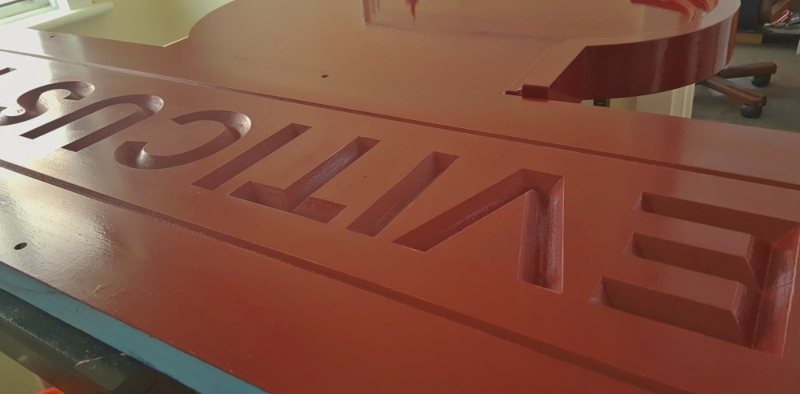 Burgundy topcoat applied to the carved Accoya wooden sign before gold leaf gilding