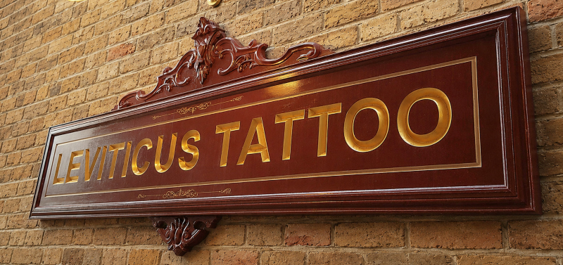 Completed gold leaf wooden sign installed on the exterior wall of Leviticus Tattoo in Loughton, Essex.