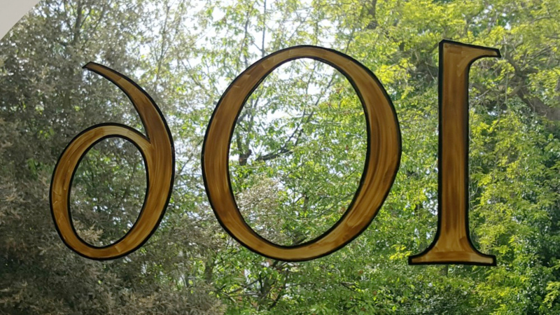 Applying the ivory paint fill to the reverse-painted fanlight number using a specialist signwriting brush.