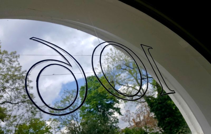 Fine black outline of the fanlight number being hand painted with a specialist signwriting brush.