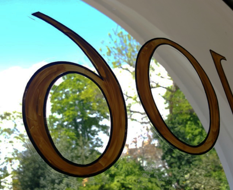 Protective varnish being applied over the reverse-painted fanlight number on the inside of the glass.