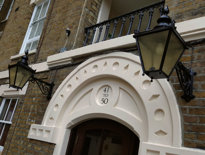 Traditional entrance numbering above a Victorian entrance arch with decorative wrought iron bracket lanterns.