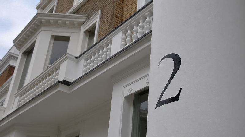 Hand painted entrance pillar number on a rendered masonry pier.
