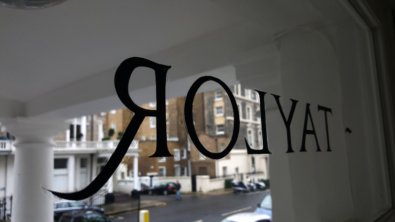 Applying protective varnish to reverse painted glass lettering.