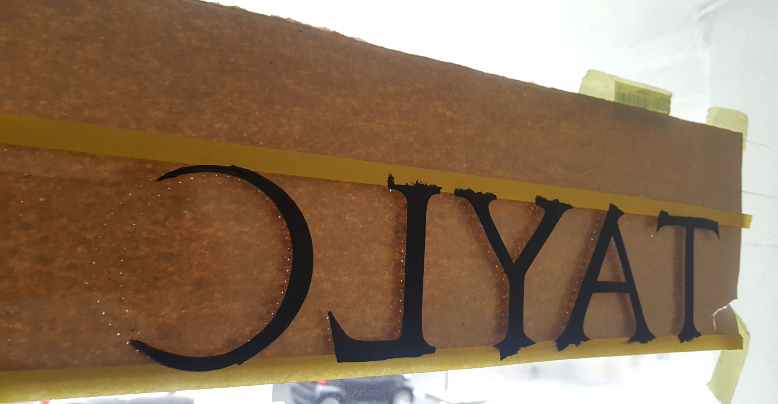 Paper template used for signwriting reverse glass lettering on a transom window.