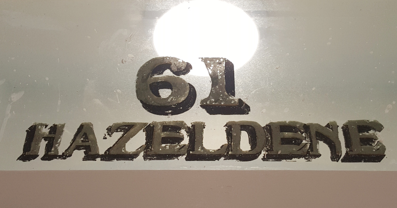 Original reverse glass house name and property numbering before restoration on the transom window of a period residence in Ealing.