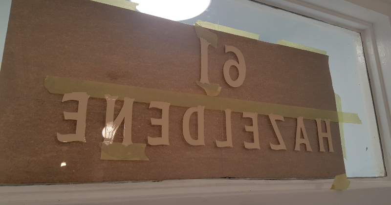Ivory reverse glass house name and property numbering hand painted onto the transom window of a period residence.