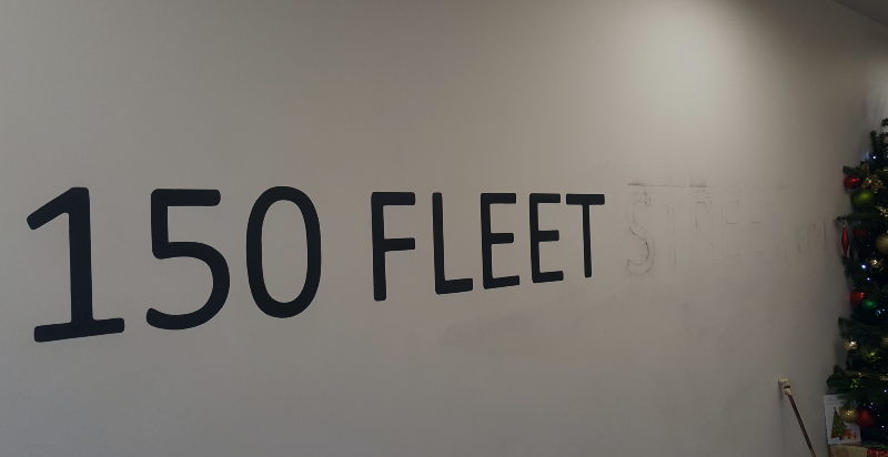 Hand painting the Fleet Street address onto the entrance wall using traditional signwriting techniques.