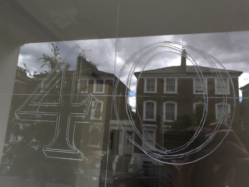 Full-size artwork positioned on the exterior of the fanlight to establish the layout for traditional gold leaf numbering.