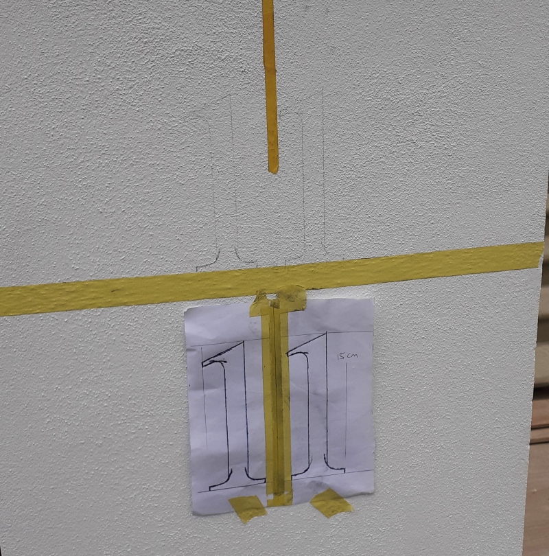 Marking out architectural entrance pier numbering on a rendered entrance pier using a full-size template at a Kensington residence.