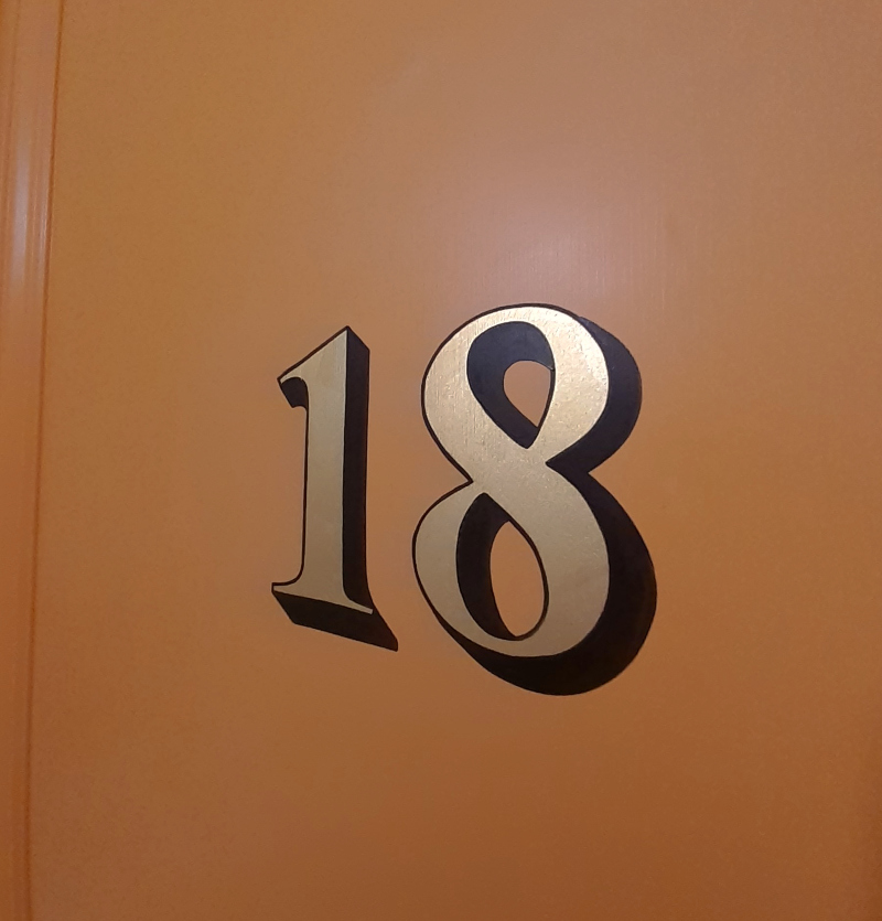 Completed genuine gold leaf architectural door numbering on the entrance of a period apartment in Bayswater.