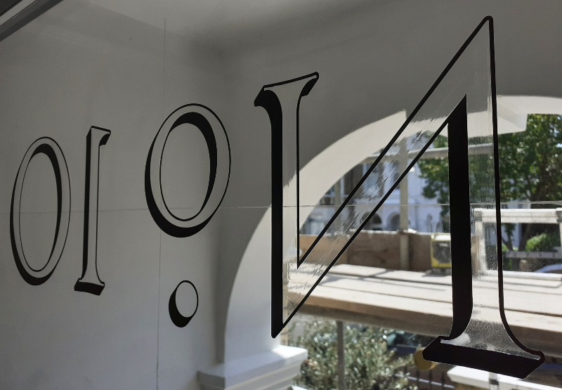 Applying traditional oil gilding size to architectural entrance numbering before laying genuine gold leaf.