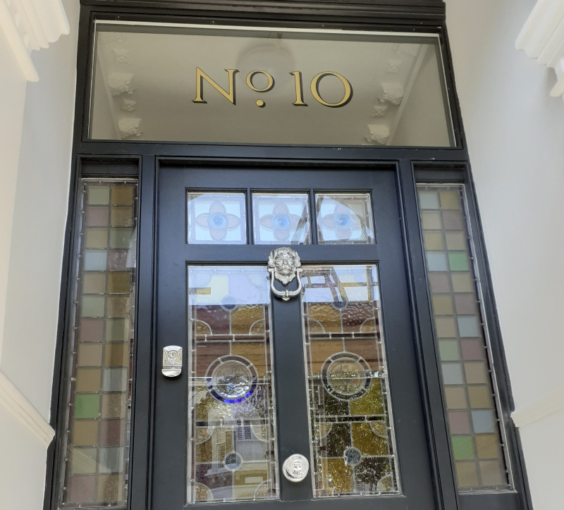 Close-up of genuine gold leaf property numbers on reverse glass with hand painted outlining and cast shadow.