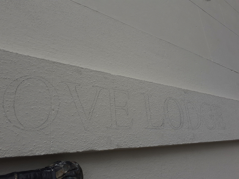 Traditional pounce pattern used to transfer the Grove Lodge property name onto a stippled masonry lintel before painting.