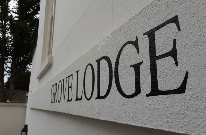 Painted property name lettering applied directly to a stippled masonry lintel using traditional signwriting techniques.
