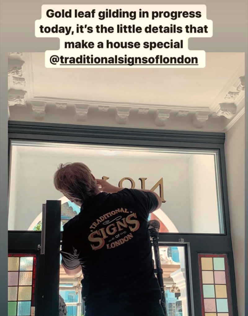 Traditional signwriter completing genuine gold leaf architectural entrance numbering on reverse glass.