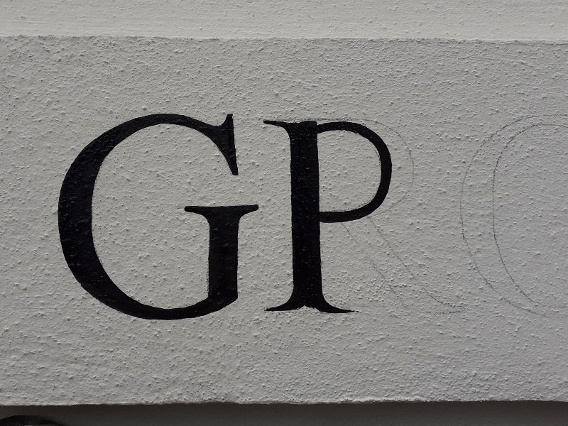 Close-up of architectural property lettering being painted onto textured masonry using traditional brush techniques.
