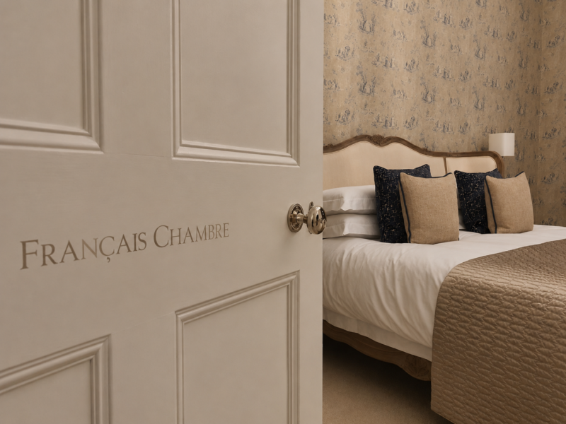 Architectural bedroom door lettering in white gold on an ivory-painted door within a historic private residence.