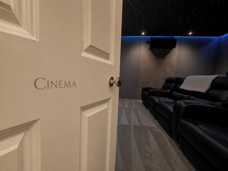 White gold Roman serif lettering identifying the ciema room within a historic Edwardian private estate.