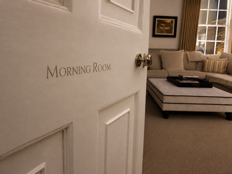 White gold Roman serif lettering applied to an ivory door as part of an architectural wayfinding scheme for a prestigious private estate.