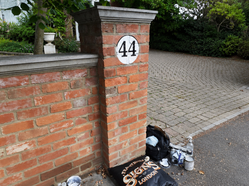 Residential signwriting on painted brick gate piers in London