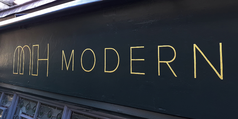 Professional signwriter applying gold leaf lettering by hand